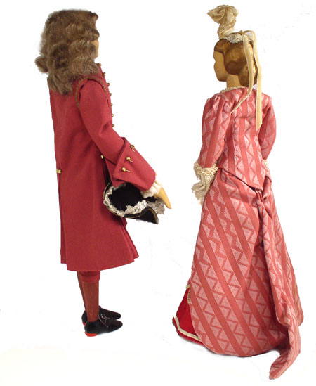 Back view of husband and wife wooden dolls dressed in period costumes of America in 1708