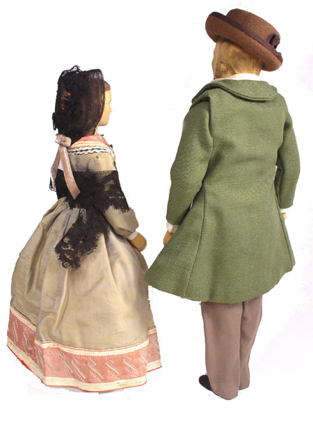 Back view of husband and wife wooden dolls dressed in period costumes of America in 1840