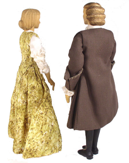 Back view of husband and wife wooden dolls dressed in period costumes of America in 1677