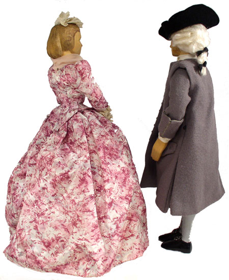 Back view of husband and wife wooden dolls dressed in period costumes of America in 1736