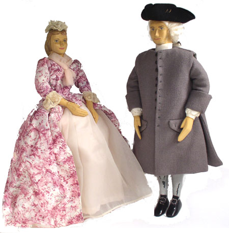 Front view of husband and wife wooden dolls dressed in period costumes of America in 1736