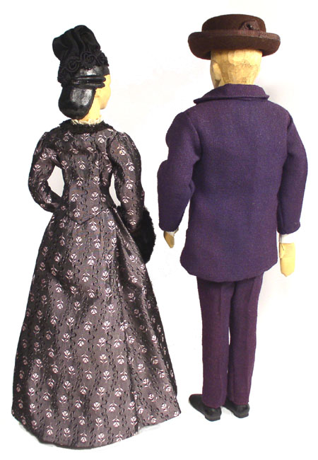 Back view of husband and wife wooden dolls dressed in period costumes of America in 1875