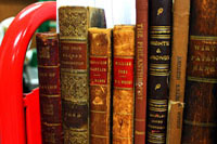 Selection of leather and cloth bound books which need repairs on a red book cart.