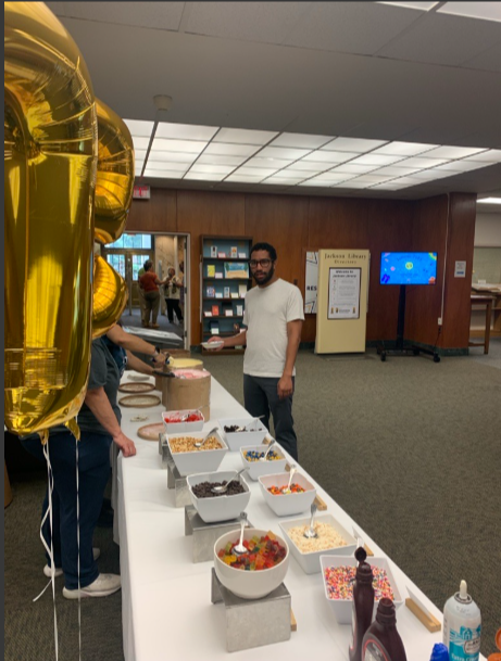 Man standing in front of a table with ice cream and toppings.