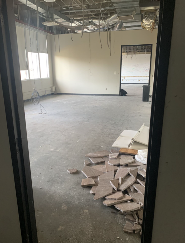 An empty room with ceiling and vent exposed. Debris is on the ground.