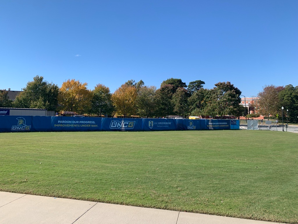 Large lawn area with blue construction fencing.
